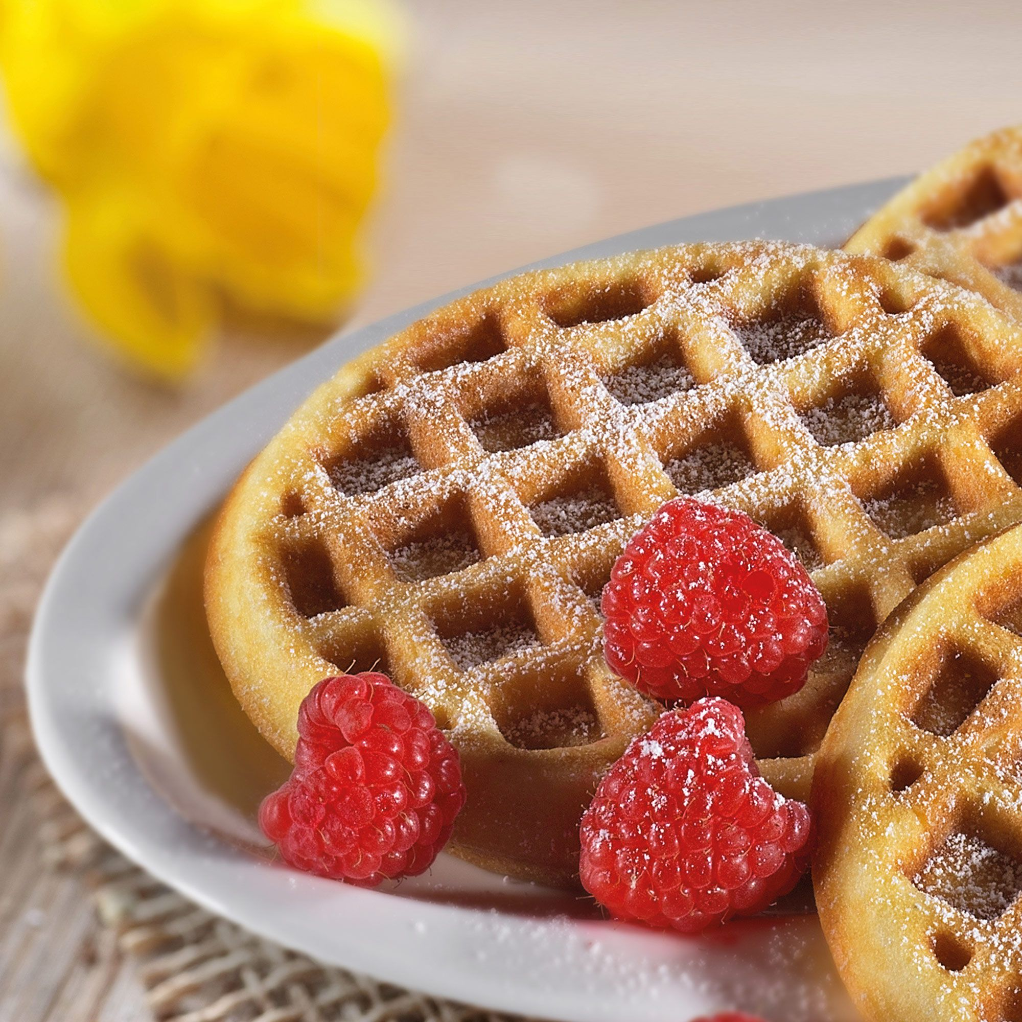 Frische runde Mini-Waffeln mit Puderzucker und Himbeeren